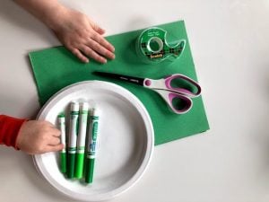 Supplies for Peas in a Pod Craft, including markers, paper plate, scissors, tape and green paper