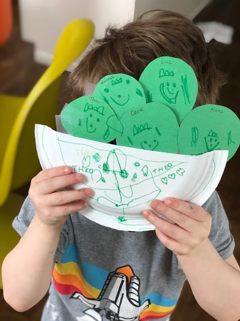 child holding our family Peas in a Pod Craft, with peas labelled as different members of the family