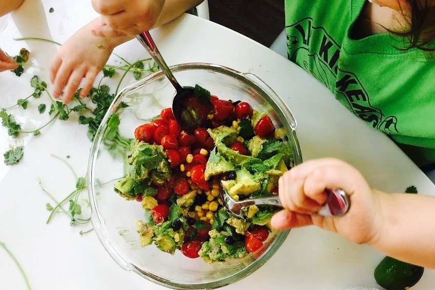 Child stirring avocado salad