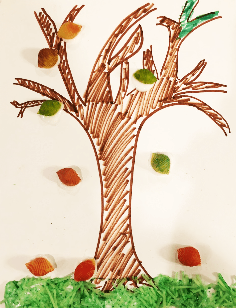 tree drawn on paper with colored shell noodles as leaves and green-dyed parmesan as grass