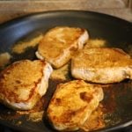 4 pork chops browning in pan