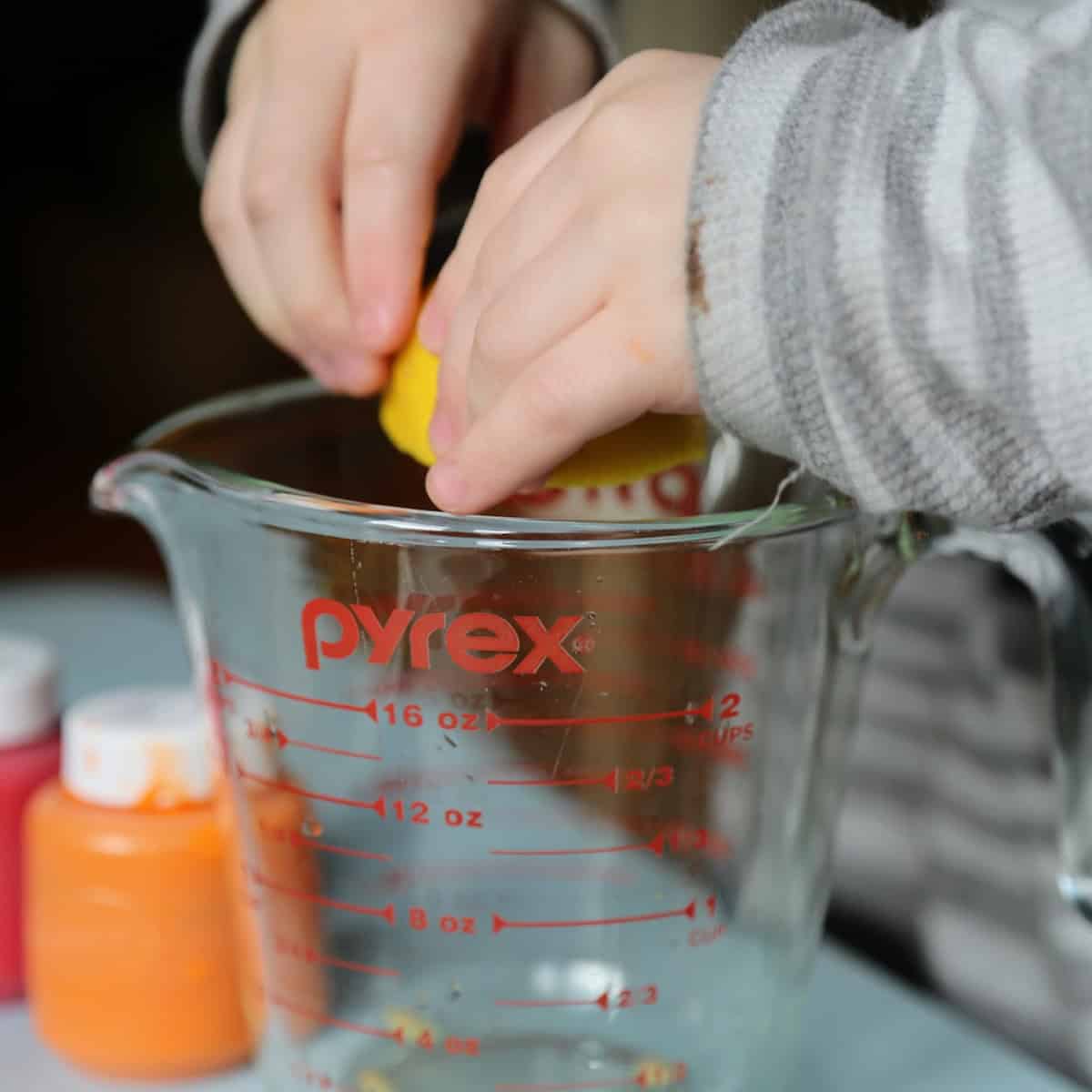 Child juicing a lemon over a glass bowl.
