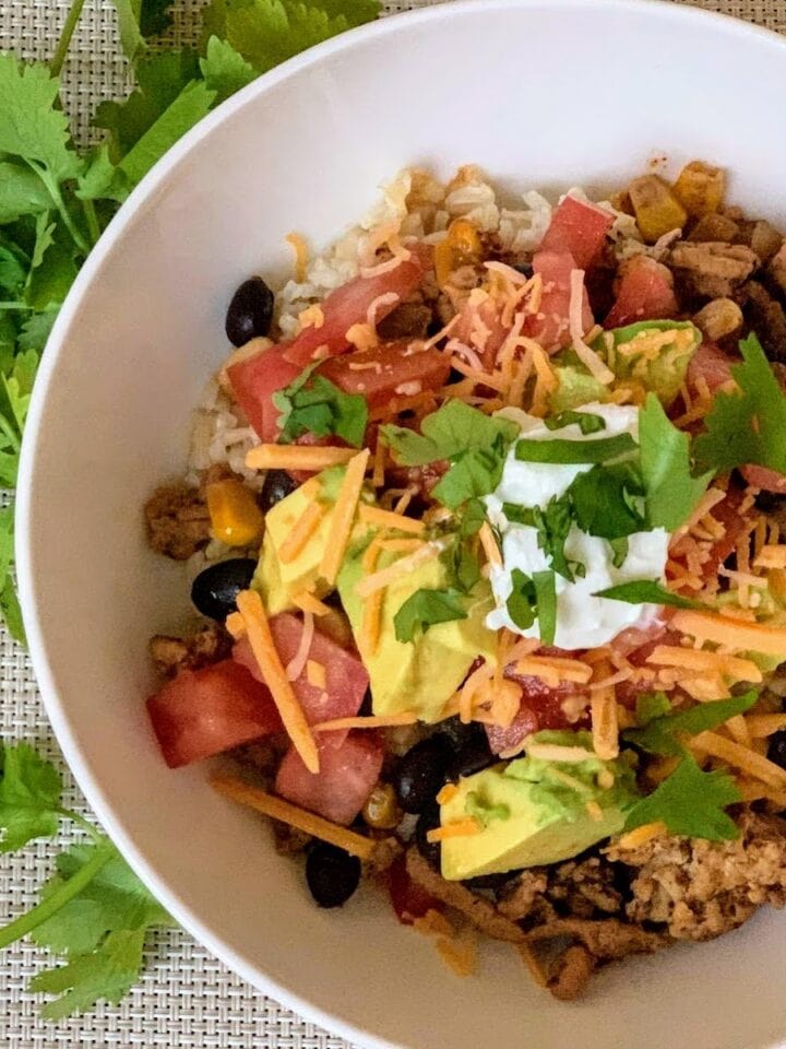 white bowl with ground turkey, taco toppings and cilantro