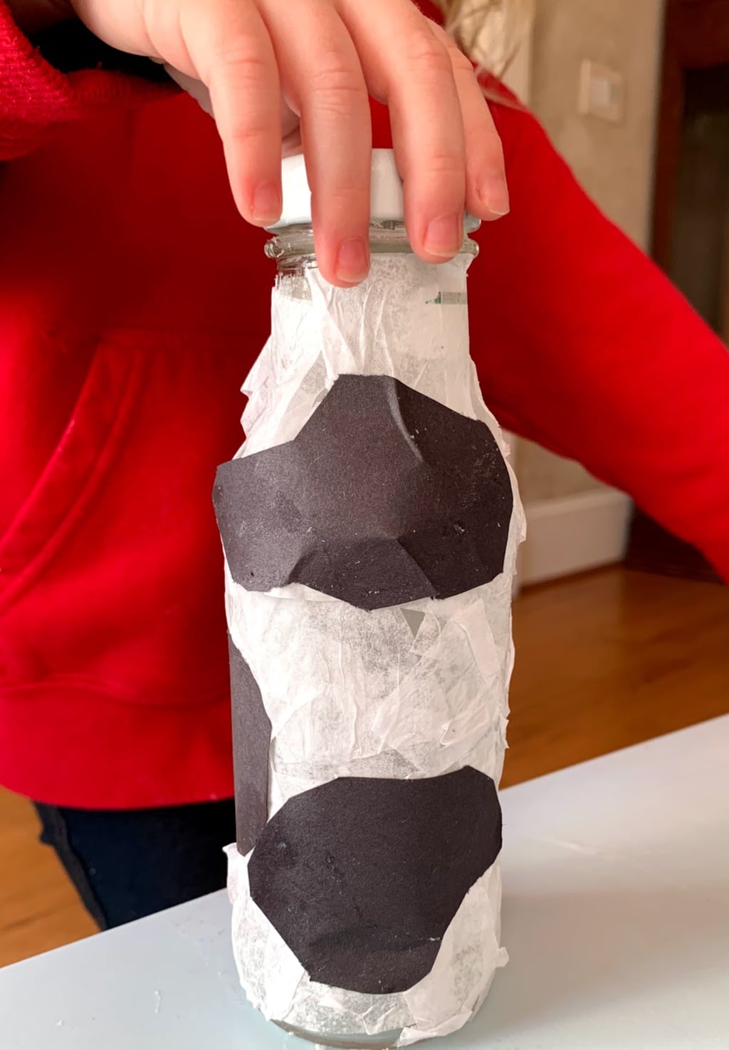 Glass bottle covered in black and white tissue paper