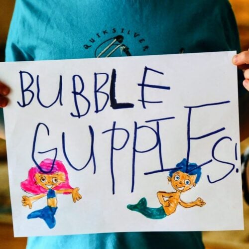 child holding sign that says bubble guppies