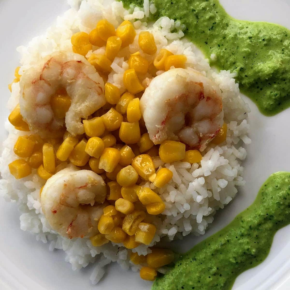 shrimp with rice corn and  green sauce on white plate