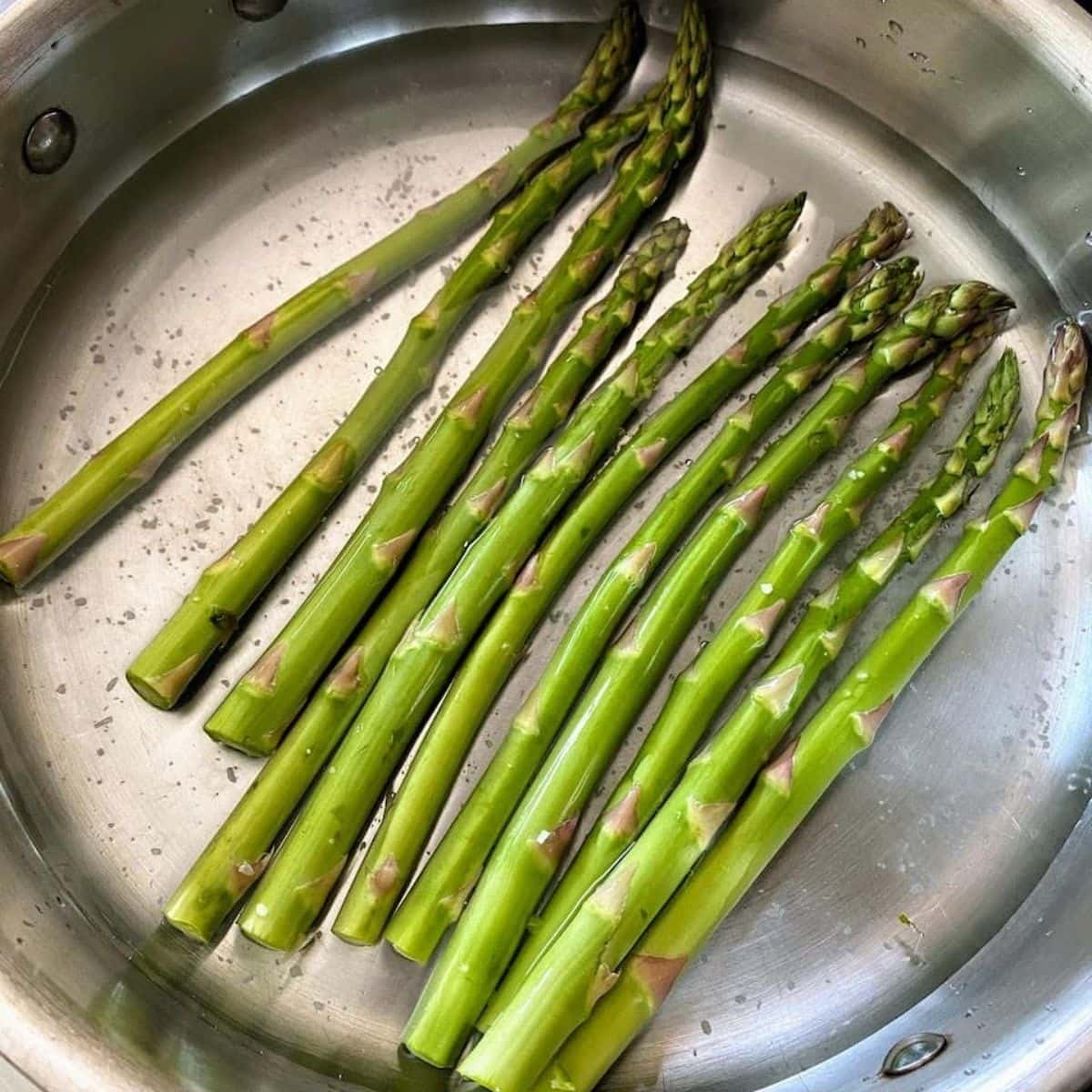 asparagus in shallow water in medium pan