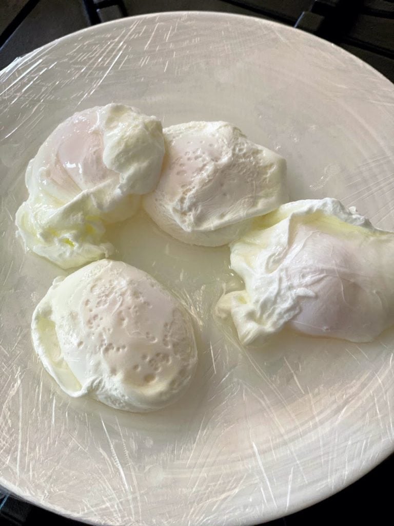 four poached eggs sitting on plastic-wrapped plate