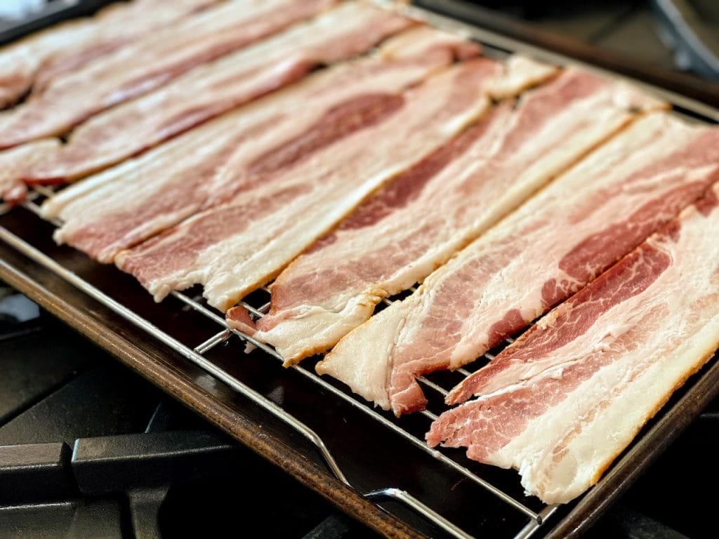 strips on raw bacon on wire rack in rimmed baking sheet