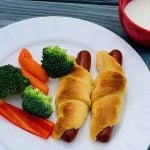 crescent dog on plate with broccoli, red peppers and carrots