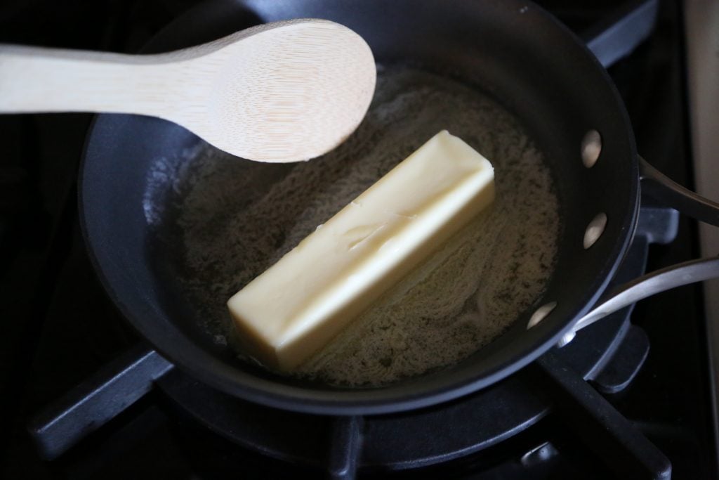 Child stirring butter as it cooks on stove