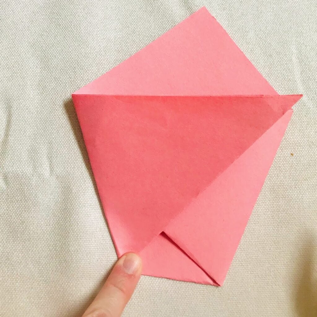 child securing origami paper bag closed