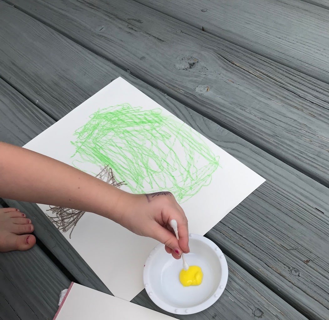 child dipping qtip into yellow paint