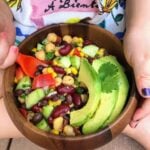 child holding brown bowl of beans and avocado