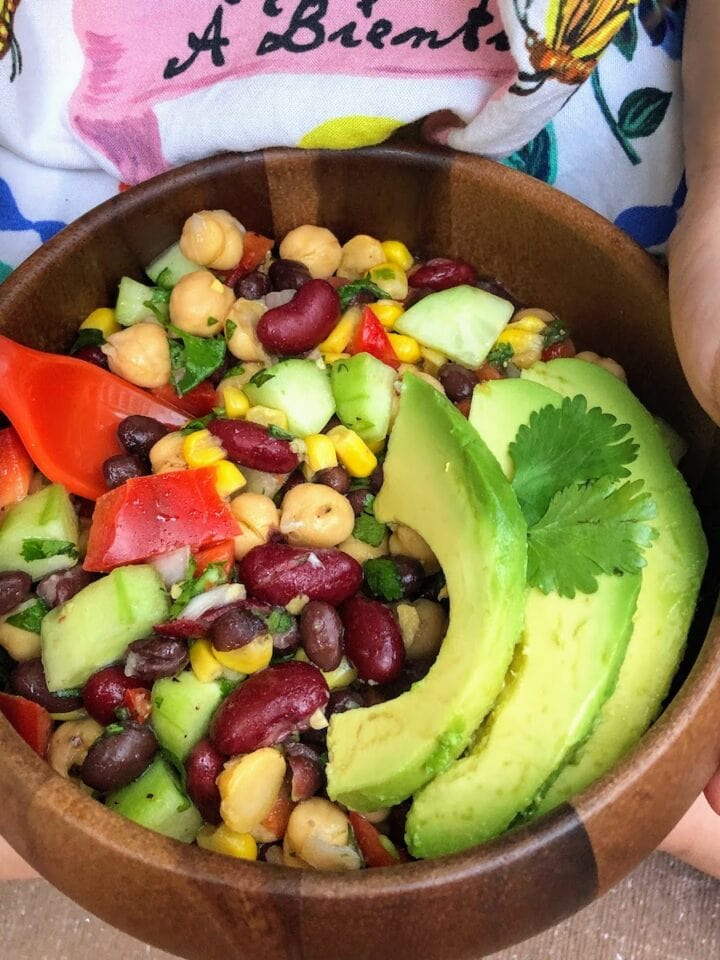 child holding brown bowl of beans and avocado