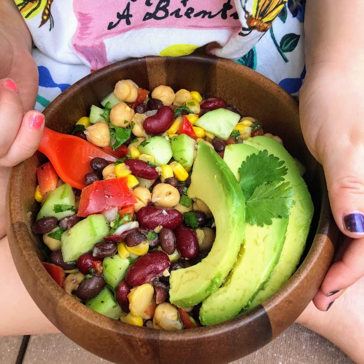 child holding brown bowl of beans and avocado