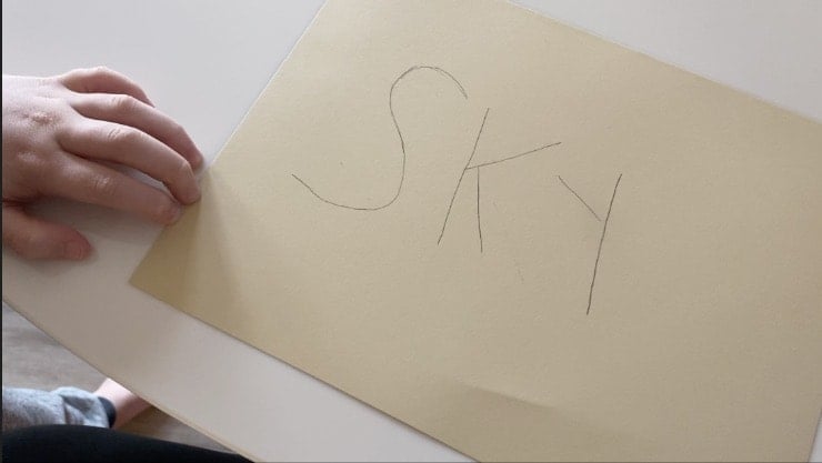the word sky written in pencil on tan paper
