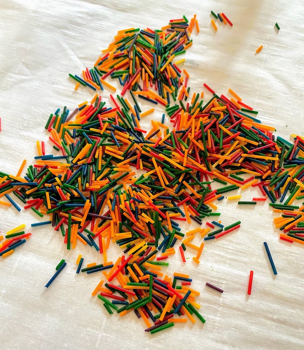 array of rainbow dyed spaghetti pieces on parchment paper