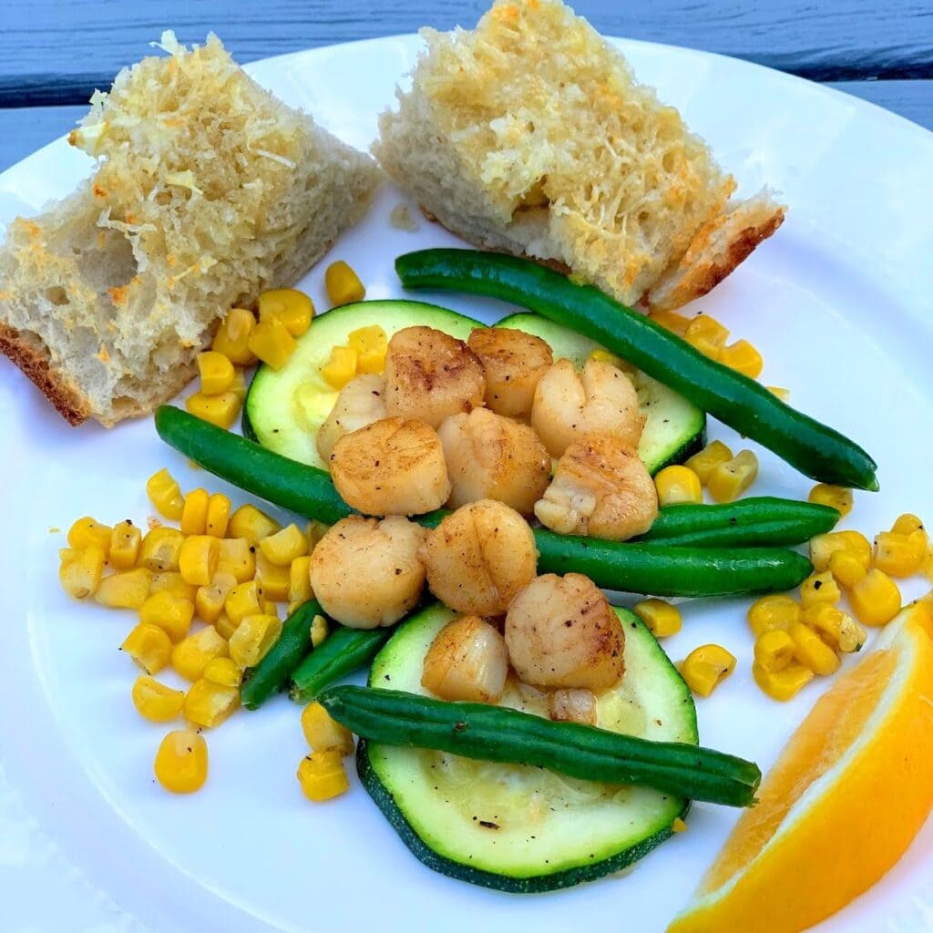 Seared Scallops with Summer Veggies and Garlic Bread on plate