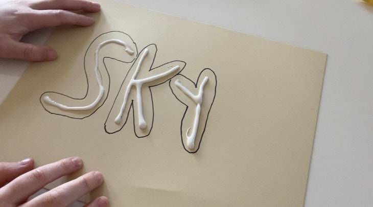 the word sky on tan paper with the letters traced in glue