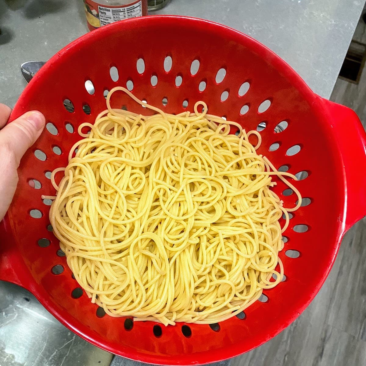 red colander full of just cooked pasta noodles
