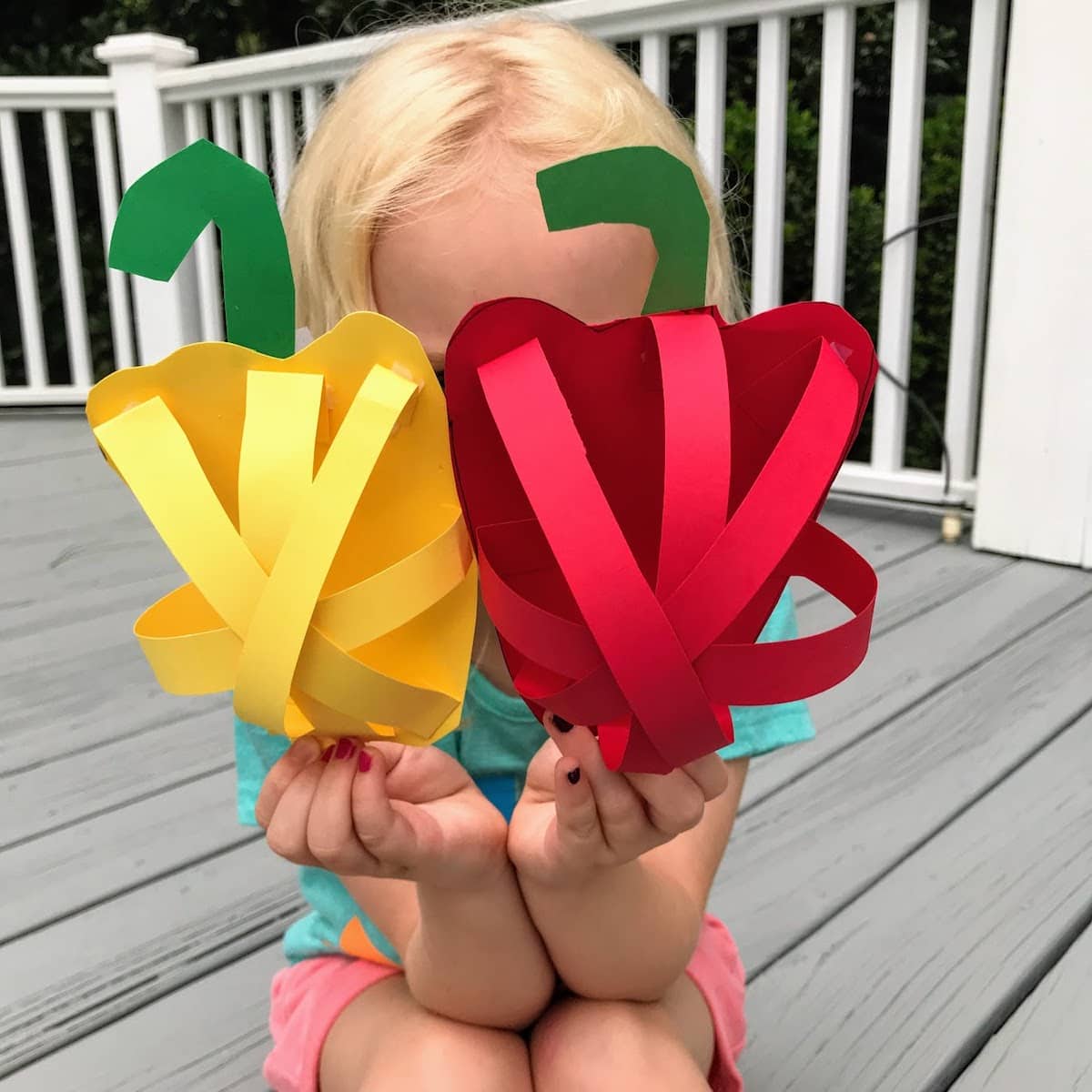 child holding two paper peppers