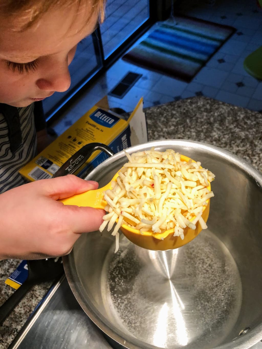 child measuring shredded cheese