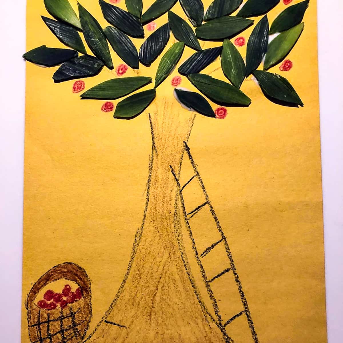 Drawing of an apple tree with a basket of apples and ladder on yellow paper, with leek food scraps as the tree leaves