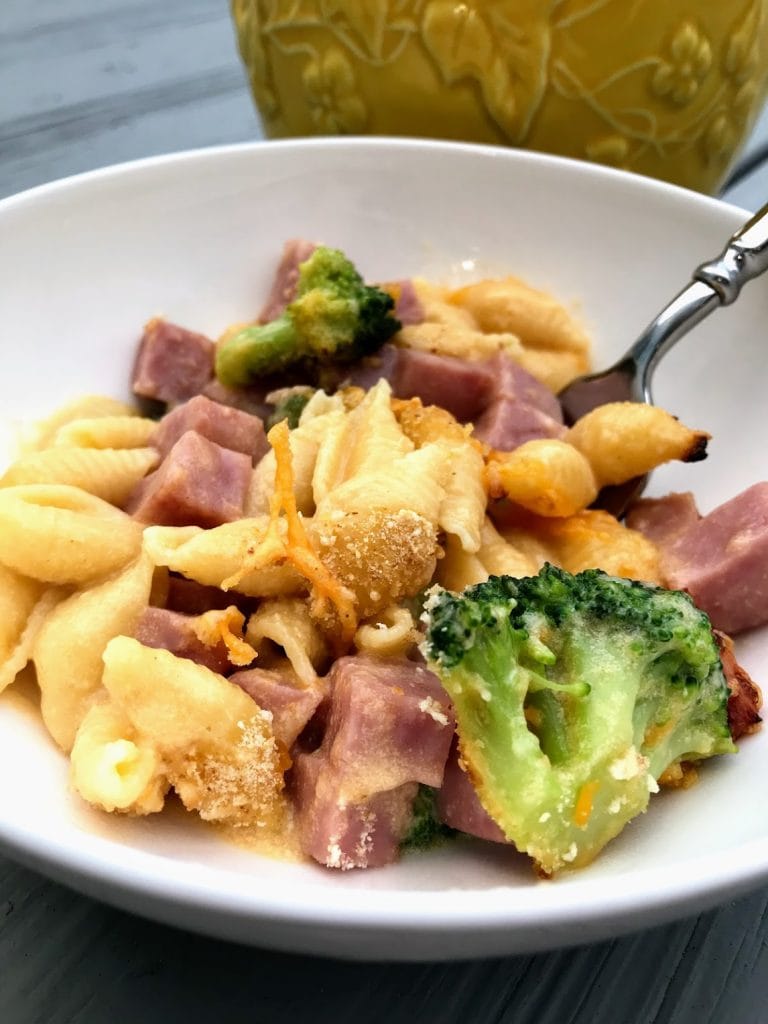 bowl of shell mac and cheese with broccoli and ham with fork