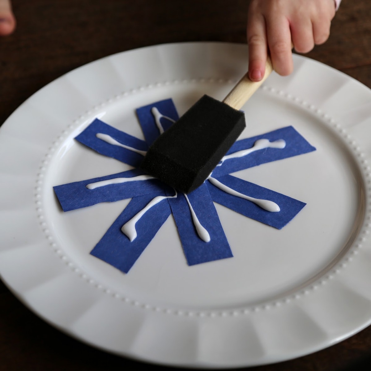child painting snowflake with glue