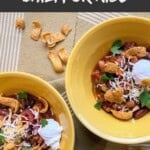 Two yellow bowls filled with chili and topped wiht sour cream.