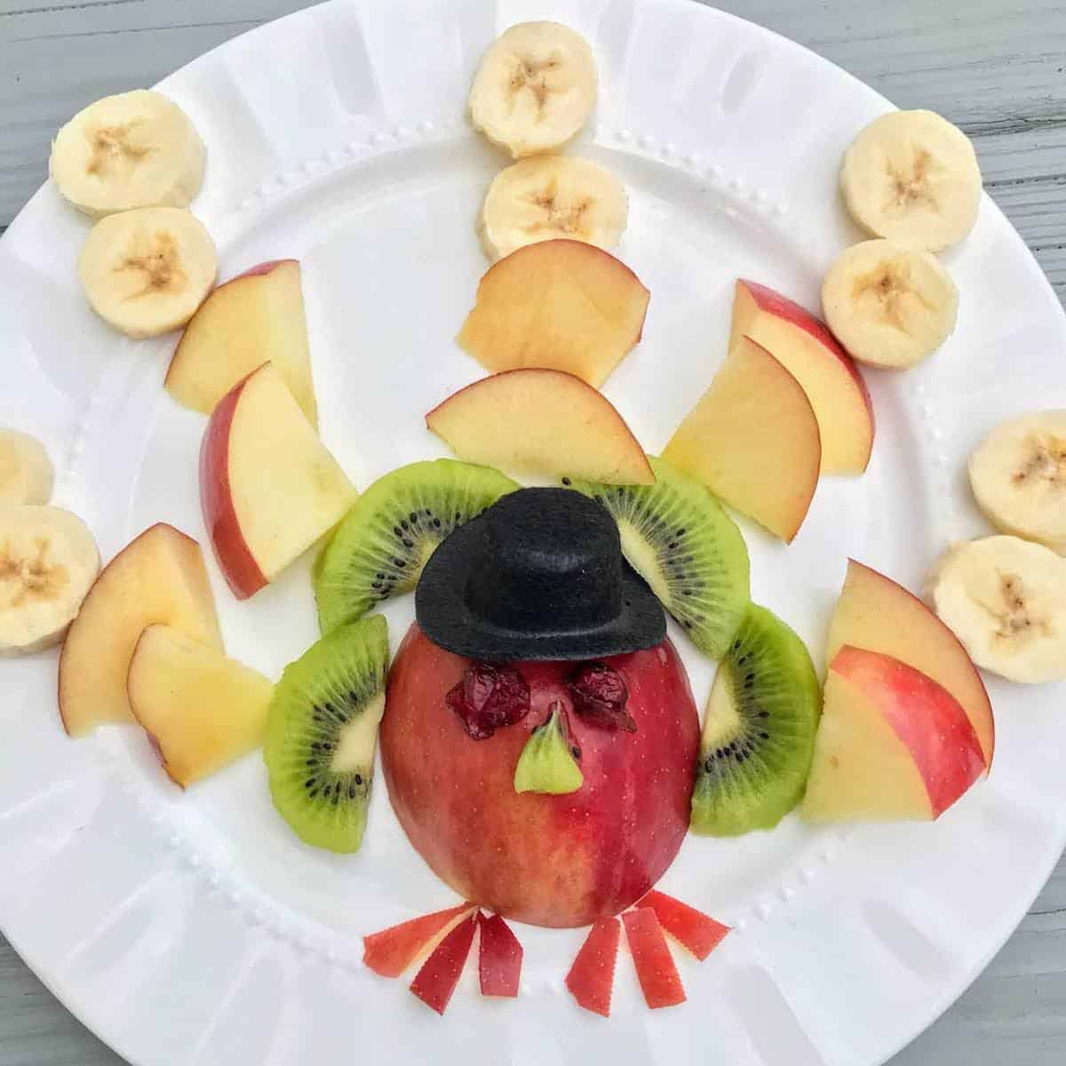 A Fruit turkey platter on a plate made with fruit slices.