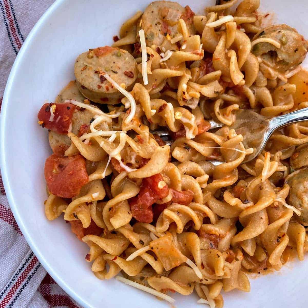 chicken sausage pasta with fork in bowl