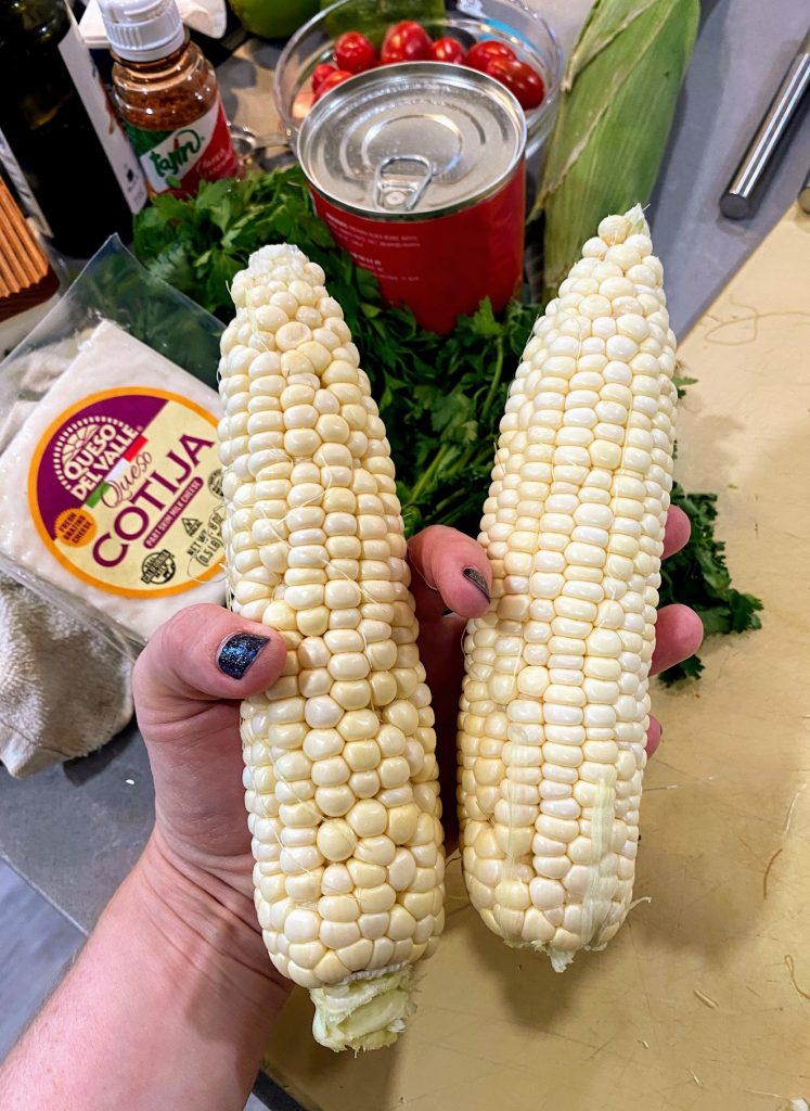 hand holding two ears of corn