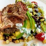 white plate with Carne Asada with Corn Salad and Chimichurri Sauce