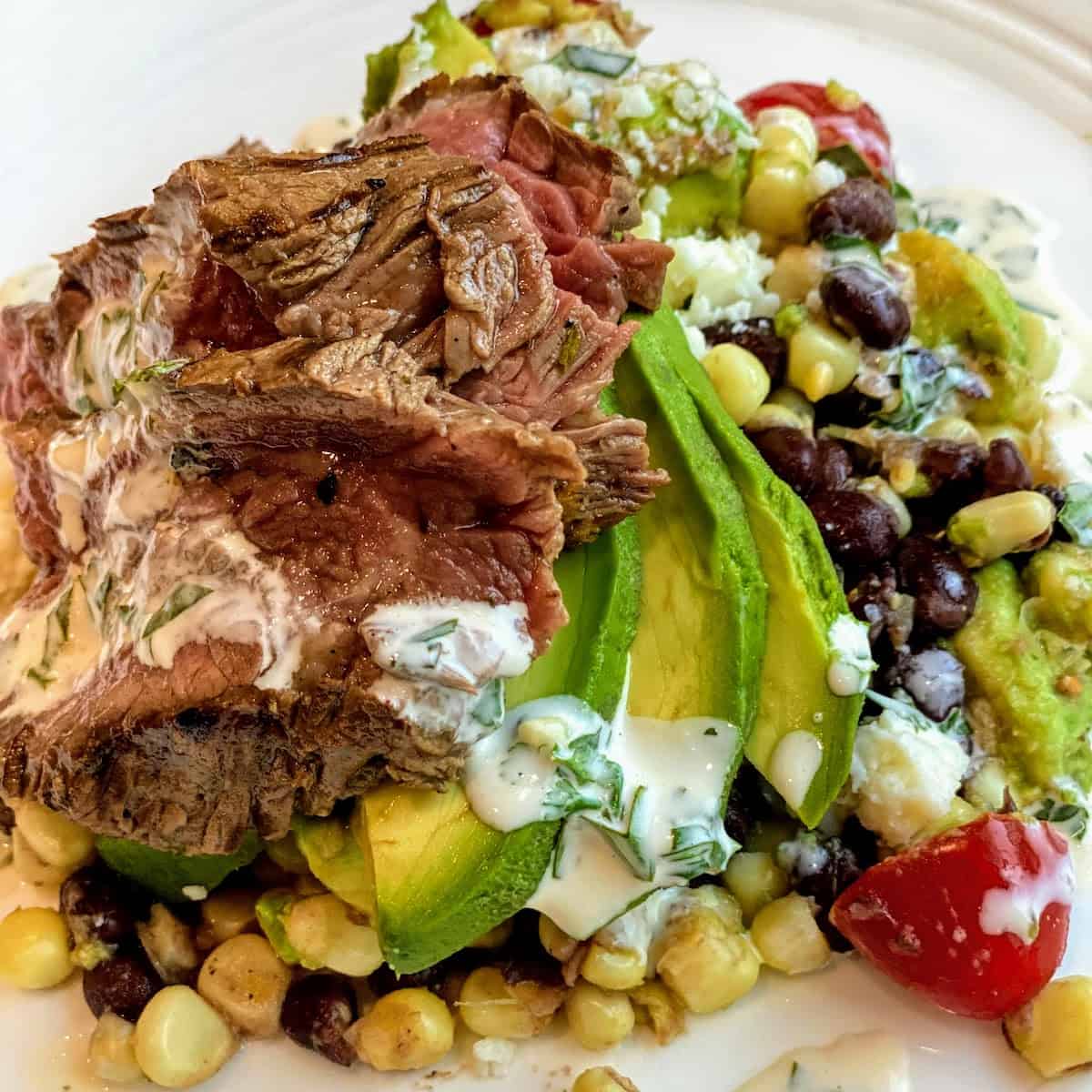 white plate with Carne Asada with Corn Salad and Chimichurri Sauce