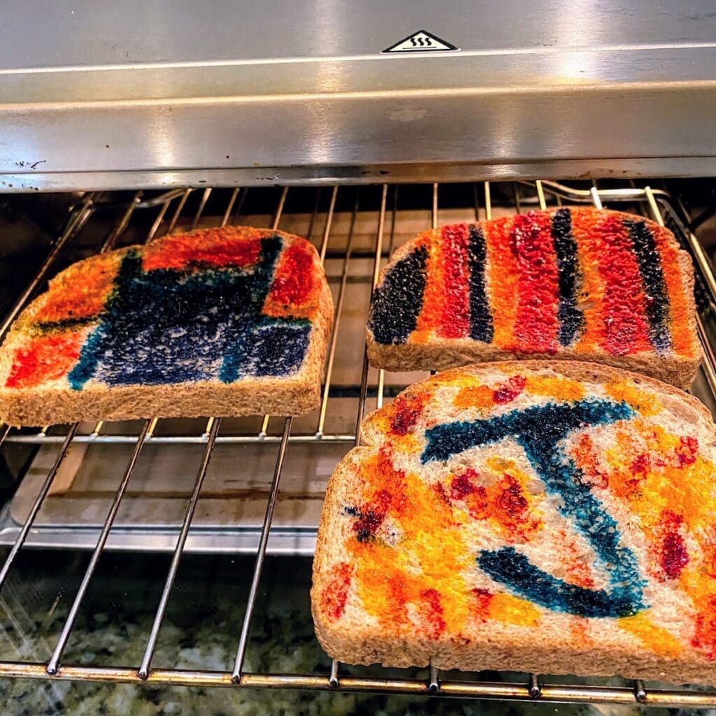 three pieces of painted toast in toaster oven