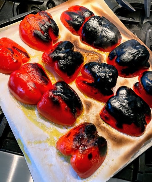 six, halved, roasted bell peppers out of the oven on a baking sheet