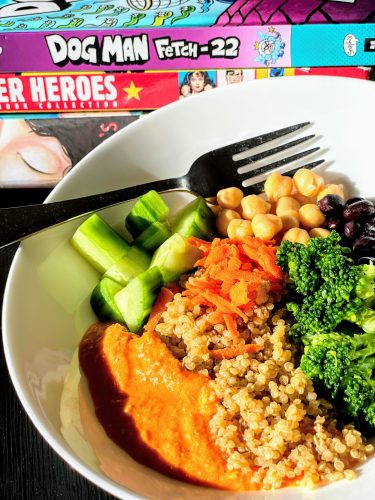 kids book next to white plate filled with veggies, romesco sauce and quinoa