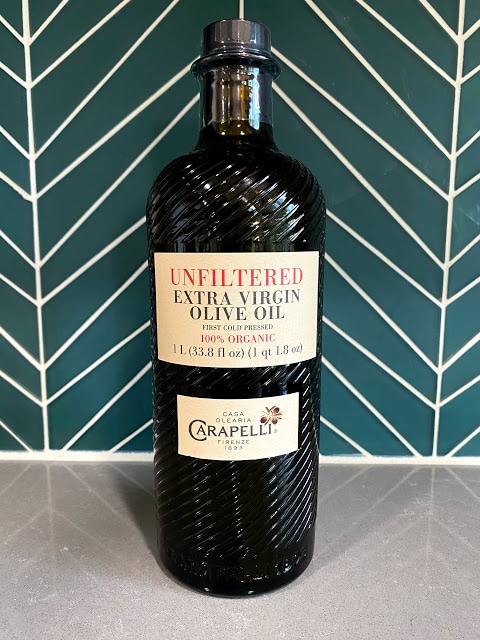 bottle of olive oil against teal tiled background