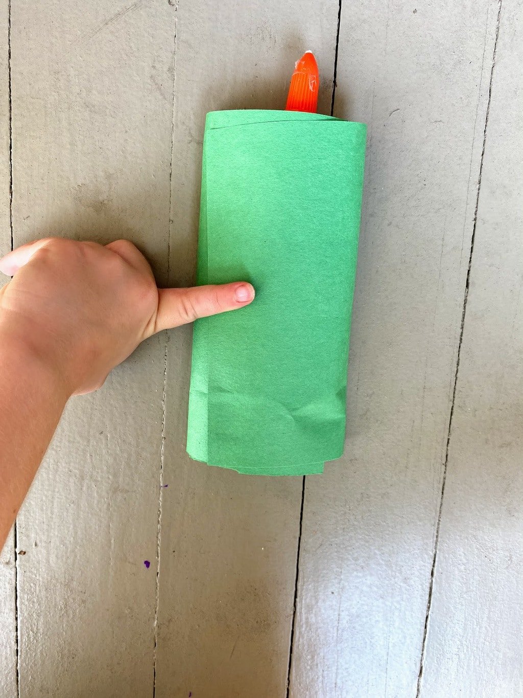 securing green paper to empty glue bottle