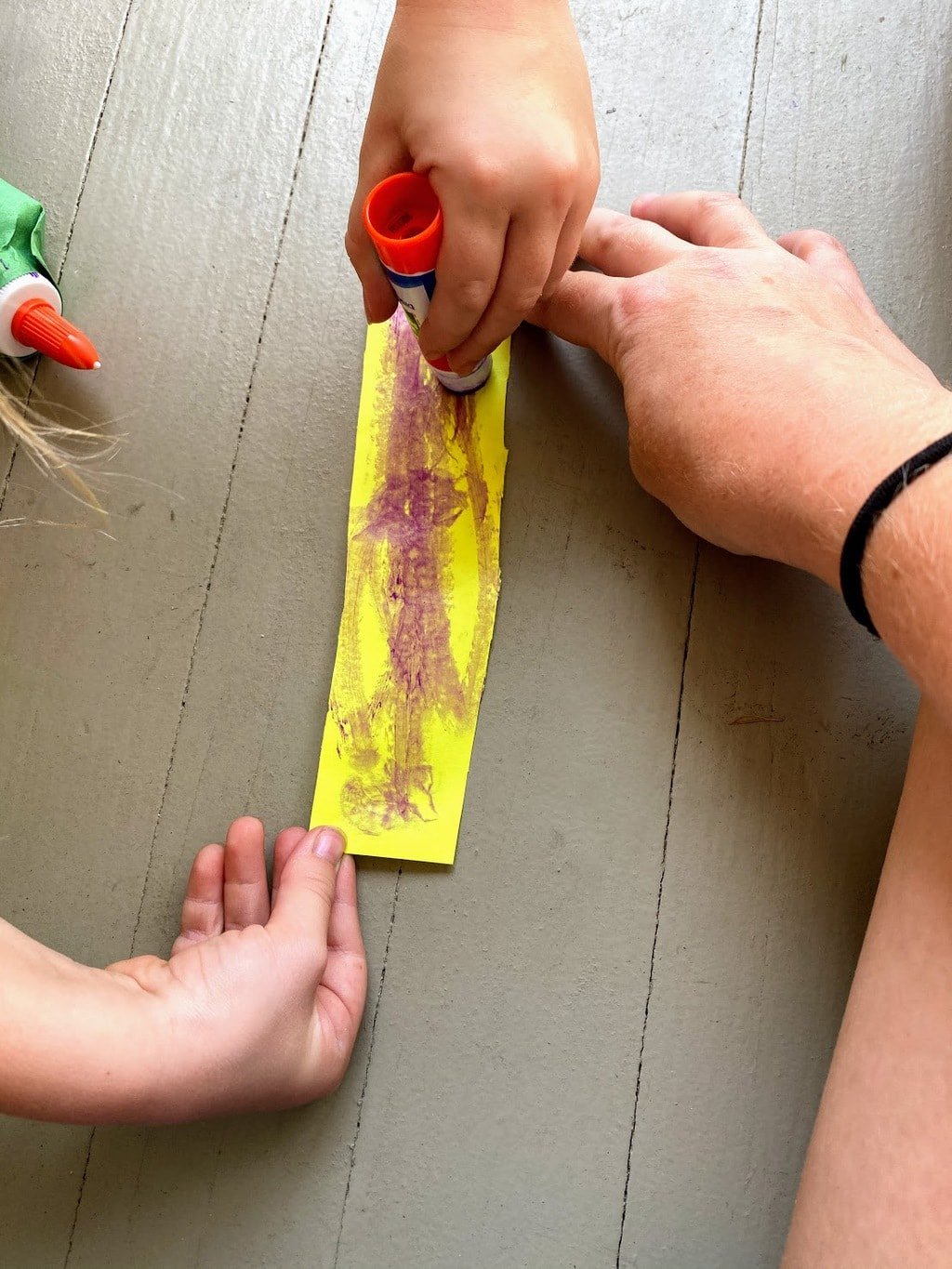 adding glue to yellow strip of paper to form lid of olive oil bottle craft