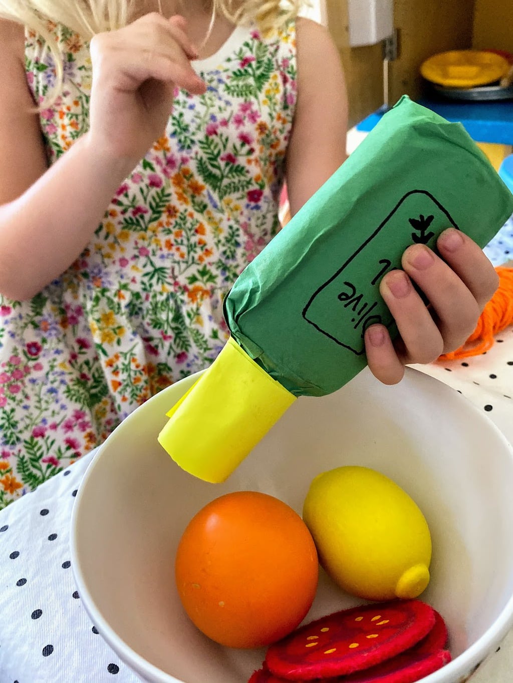 child pretending to pour olive oil on salad