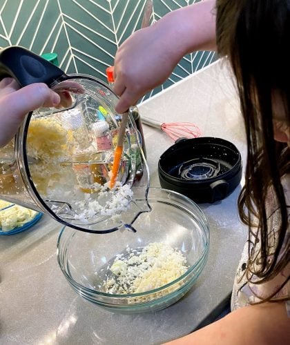 Child scraping cauliflower rice out of Vitamix container