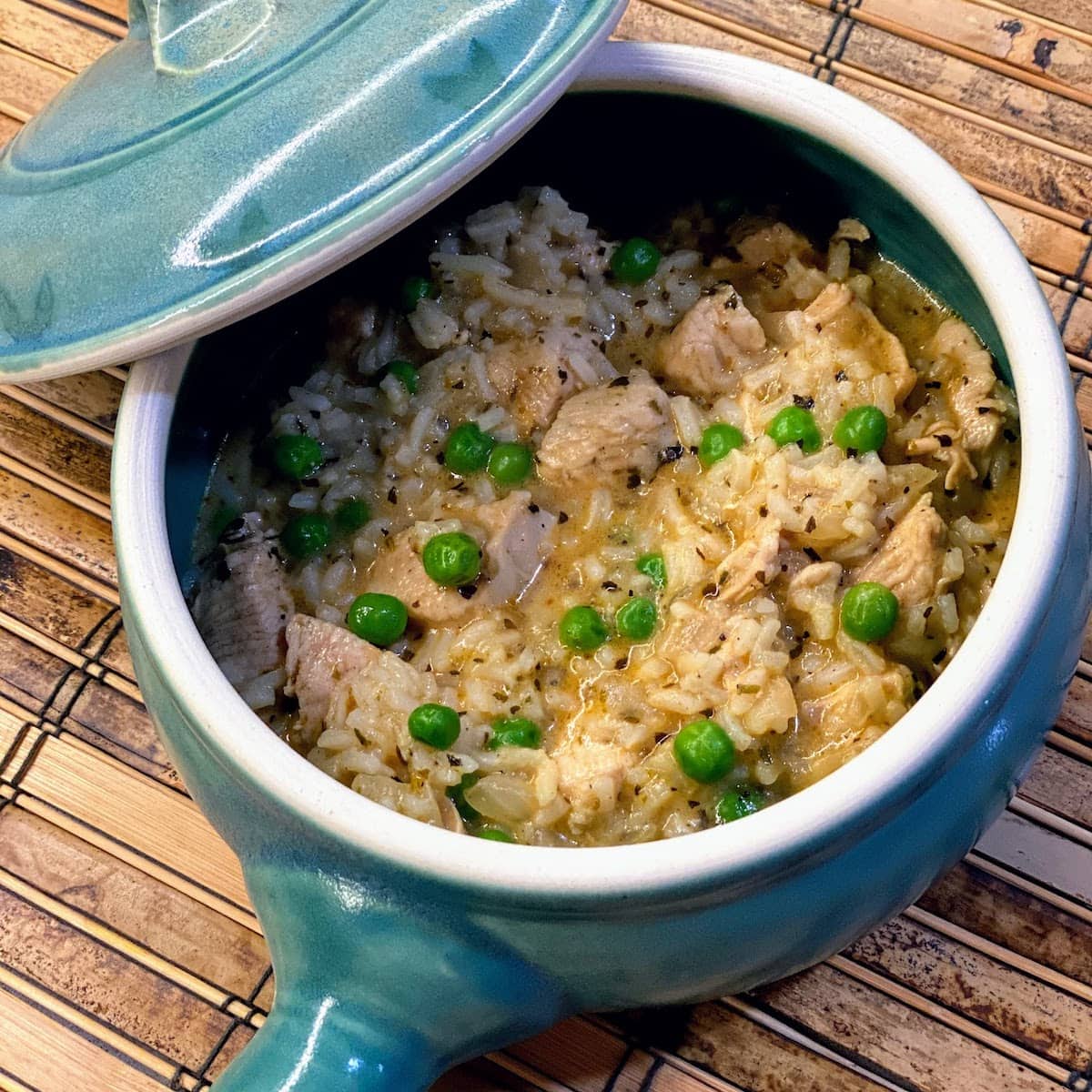 small blue crockpot filled with chicken, rice and peas