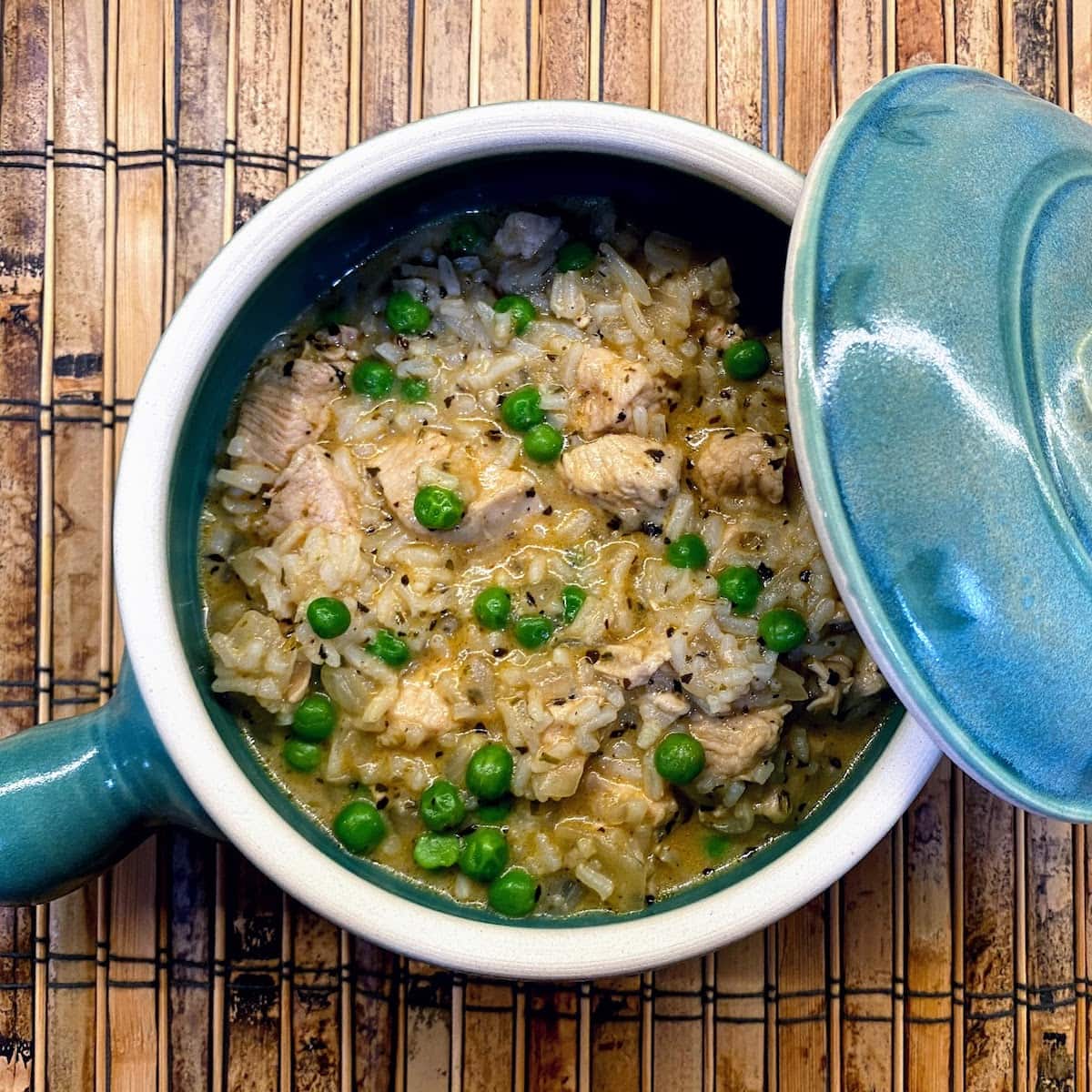 chicken, rice and peas in small blue crockpot with lid on side