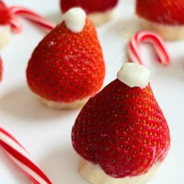 Two strawberries transformed into santa hats with melted wafers and bananas.