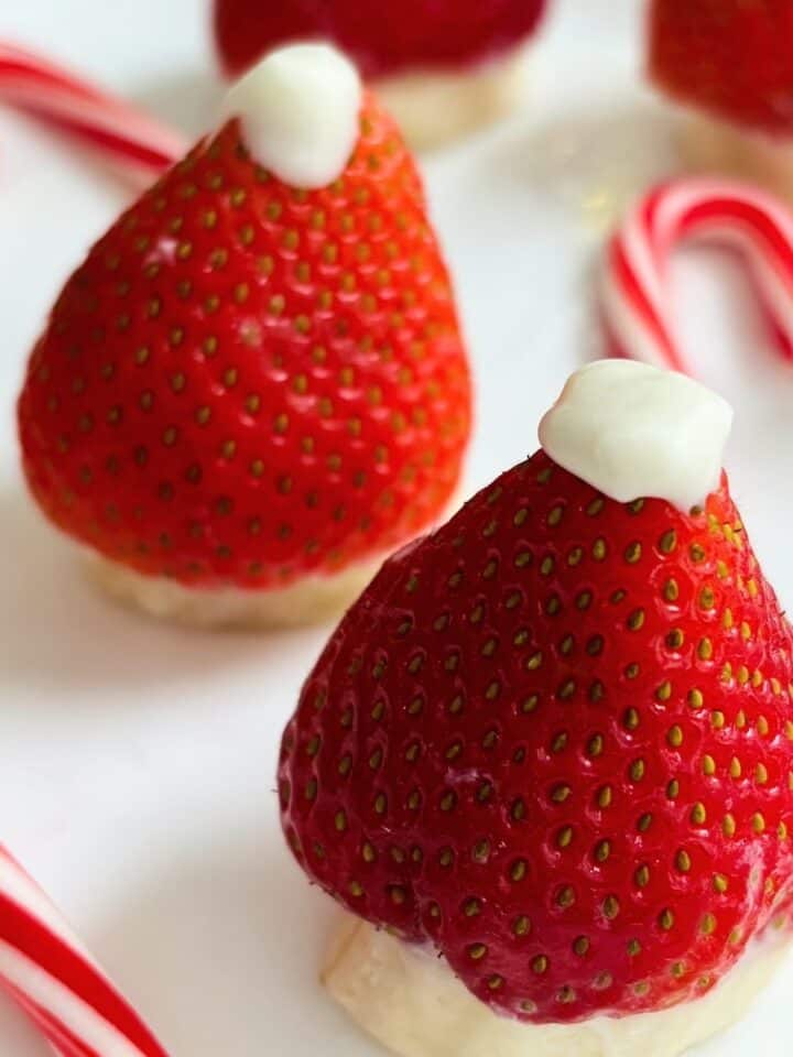 Two strawberries transformed into santa hats with melted wafers and bananas.