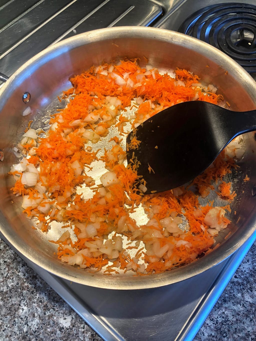 SPatula stirring carrots and other veggie in pan for turkey spaghetti sauce. 