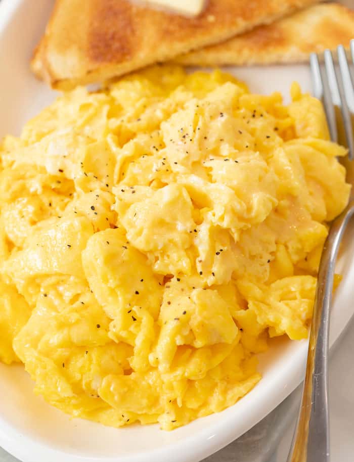 fluffy yellow scrambled eggs with toast on a plate 